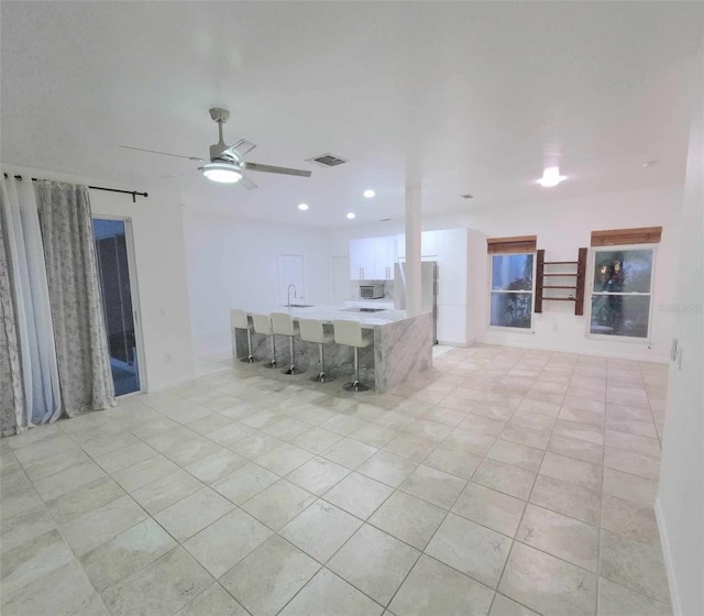 kitchen with white cabinets, sink, ceiling fan, light tile patterned floors, and stainless steel refrigerator