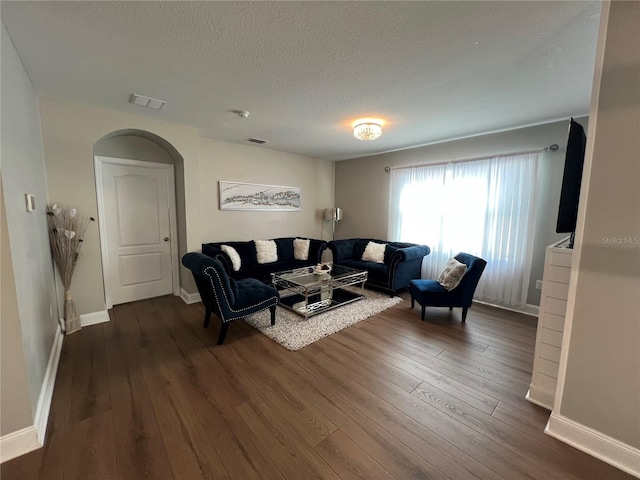 living room with a textured ceiling and dark hardwood / wood-style floors