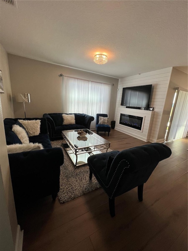 living room featuring wood-type flooring, a textured ceiling, and a fireplace