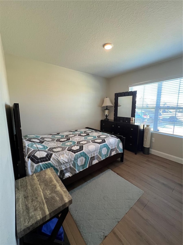 bedroom with a textured ceiling and wood-type flooring