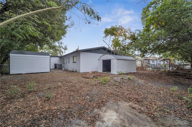 rear view of house featuring central AC unit and a shed