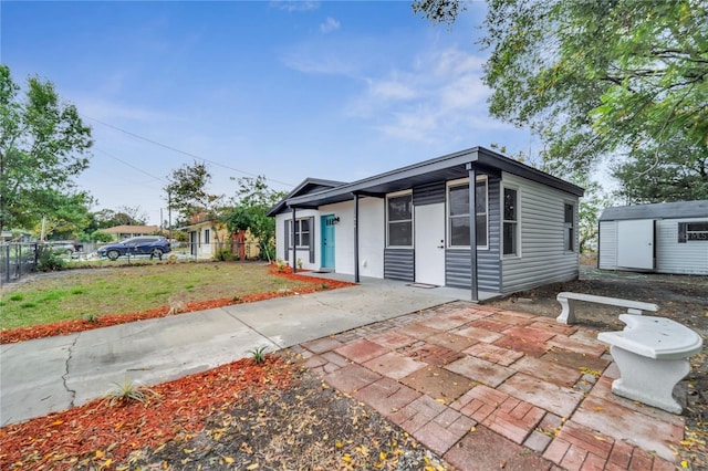 view of front of house with a patio area, a shed, and a front yard