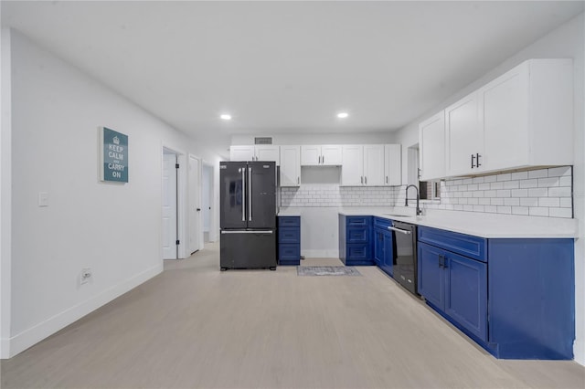 kitchen with sink, blue cabinetry, white cabinetry, black fridge, and stainless steel dishwasher