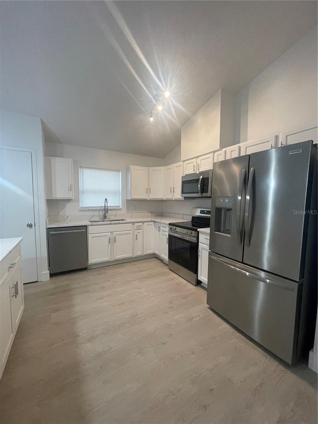 kitchen with sink, light hardwood / wood-style floors, lofted ceiling, white cabinets, and appliances with stainless steel finishes