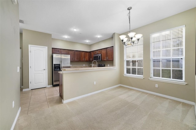 kitchen featuring light colored carpet, light countertops, a peninsula, hanging light fixtures, and stainless steel appliances