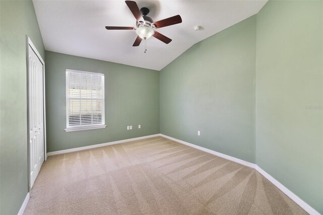 carpeted empty room featuring baseboards, a ceiling fan, and vaulted ceiling