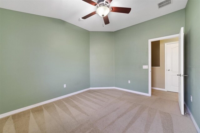 carpeted spare room featuring visible vents, a ceiling fan, baseboards, and vaulted ceiling