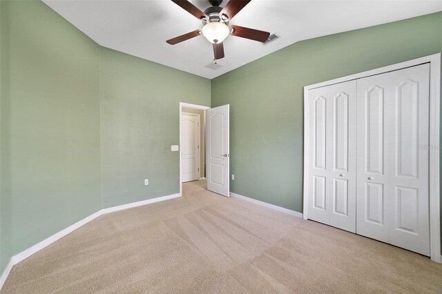 unfurnished bedroom with visible vents, baseboards, vaulted ceiling, a closet, and carpet flooring