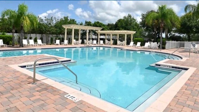 pool with a patio, fence, and a pergola