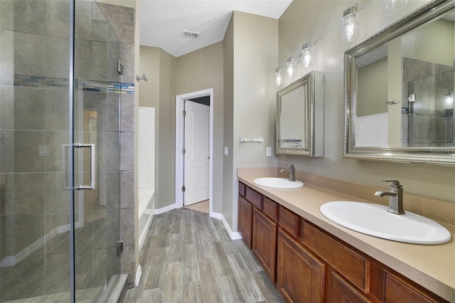 full bathroom with visible vents, a stall shower, wood finished floors, and a sink