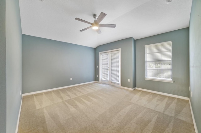 carpeted empty room featuring vaulted ceiling, a ceiling fan, and baseboards