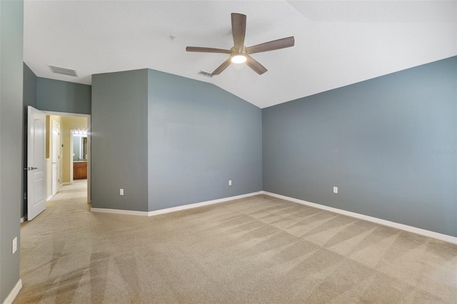 spare room with vaulted ceiling, visible vents, and light carpet