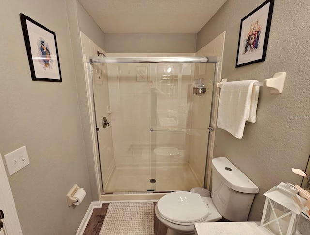 bathroom featuring a textured ceiling, toilet, walk in shower, and hardwood / wood-style flooring