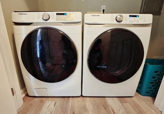 laundry room featuring washing machine and dryer and light wood-type flooring