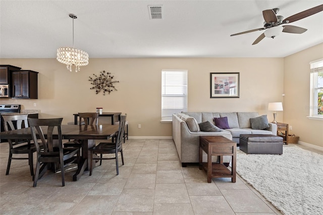 living room with light tile patterned floors, plenty of natural light, and ceiling fan with notable chandelier