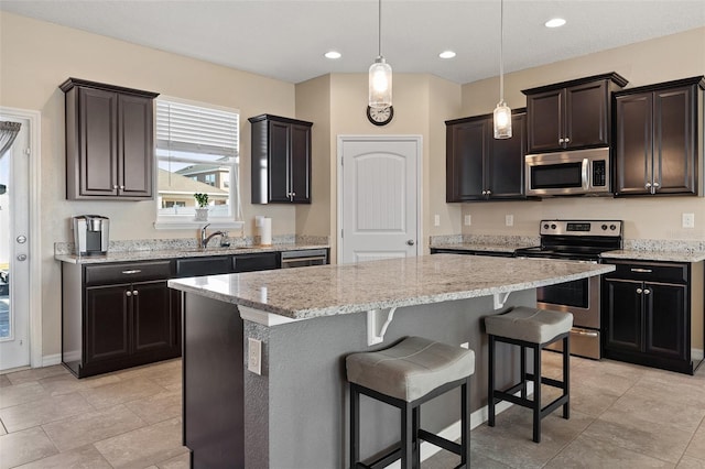 kitchen with stainless steel appliances, a kitchen breakfast bar, hanging light fixtures, light stone countertops, and a kitchen island