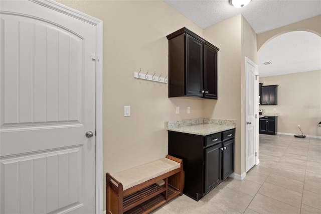 kitchen featuring light tile patterned floors, a textured ceiling, and dark brown cabinetry