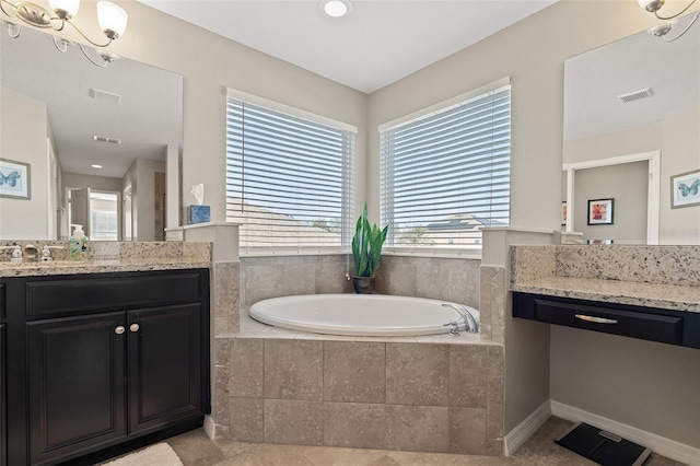 bathroom with tiled bath, tile patterned flooring, vanity, and a notable chandelier