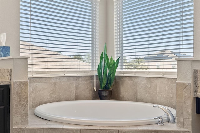 bathroom featuring a relaxing tiled tub, plenty of natural light, and vanity