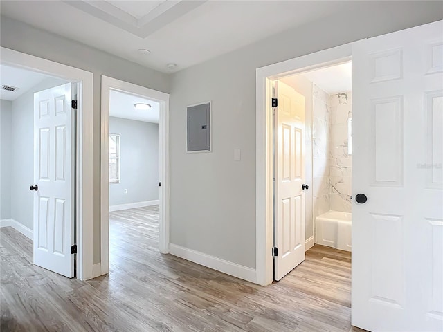 corridor with light wood-type flooring and electric panel