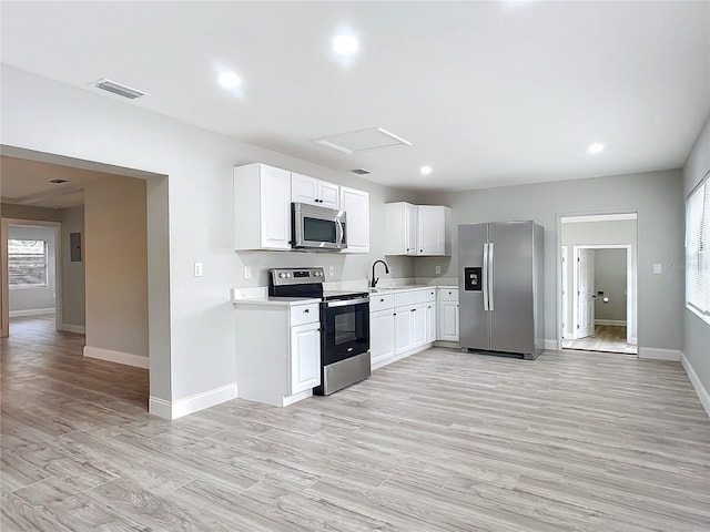 kitchen with light hardwood / wood-style floors, sink, stainless steel appliances, and white cabinetry