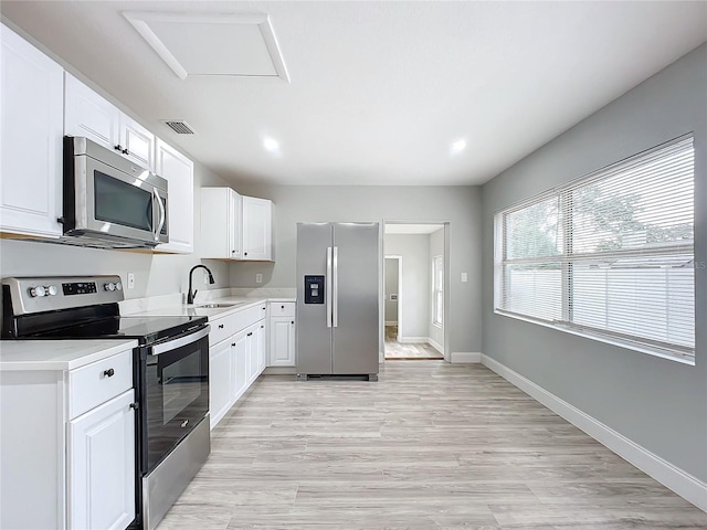 kitchen featuring sink, white cabinetry, appliances with stainless steel finishes, and light hardwood / wood-style flooring