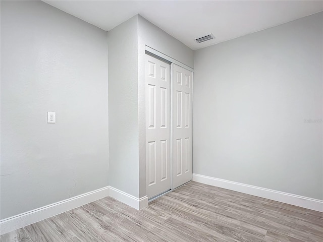 unfurnished bedroom with a closet and light hardwood / wood-style floors