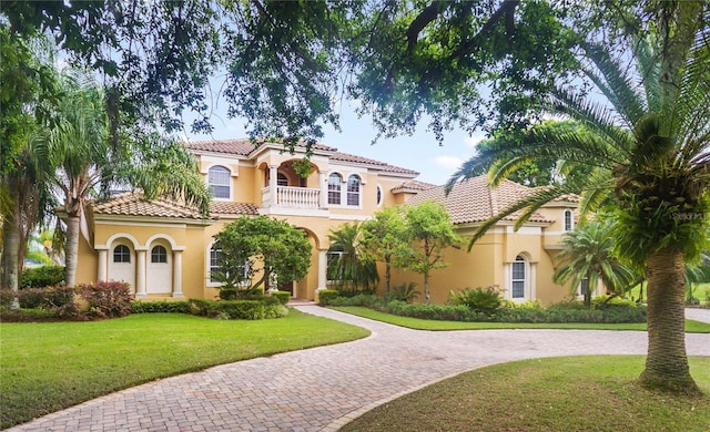 mediterranean / spanish-style home featuring a front yard and a balcony