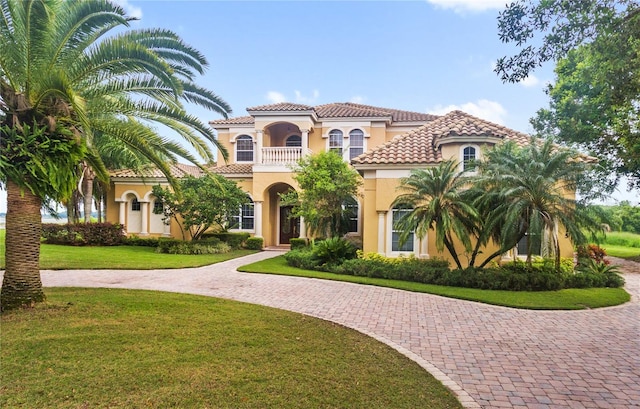 mediterranean / spanish house with a balcony and a front lawn