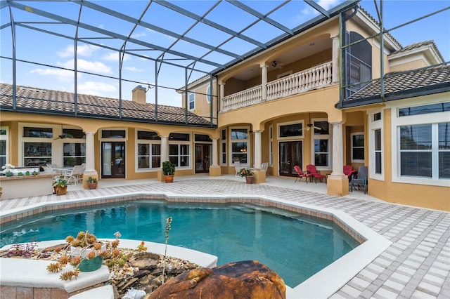 back of property featuring ceiling fan, a balcony, a patio, and glass enclosure