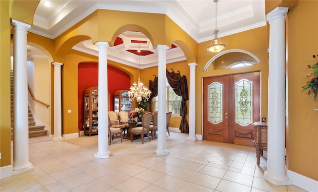 tiled entrance foyer with a towering ceiling, ornamental molding, and a notable chandelier