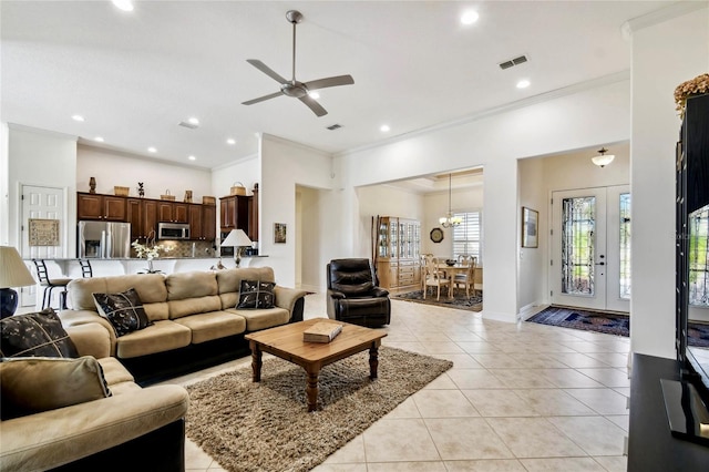 living room with ceiling fan with notable chandelier, light tile patterned floors, and crown molding