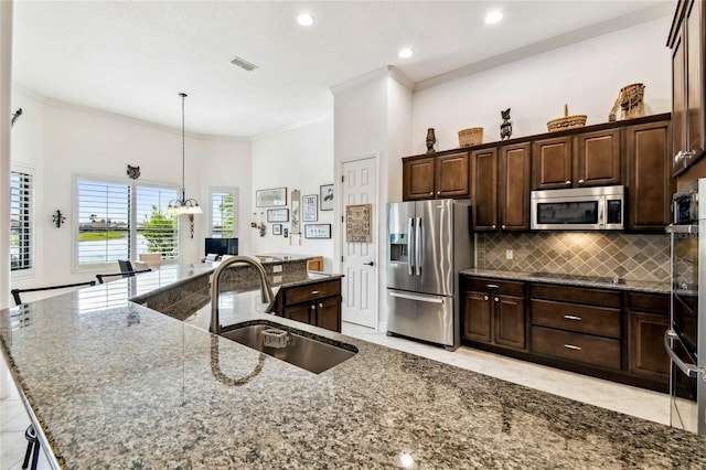 kitchen with appliances with stainless steel finishes, backsplash, dark stone counters, a spacious island, and sink