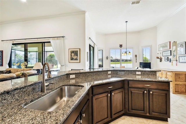 kitchen with dark stone countertops, light tile patterned floors, sink, and an inviting chandelier