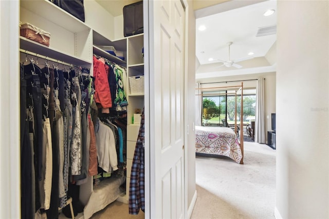 walk in closet with ceiling fan, light colored carpet, and vaulted ceiling