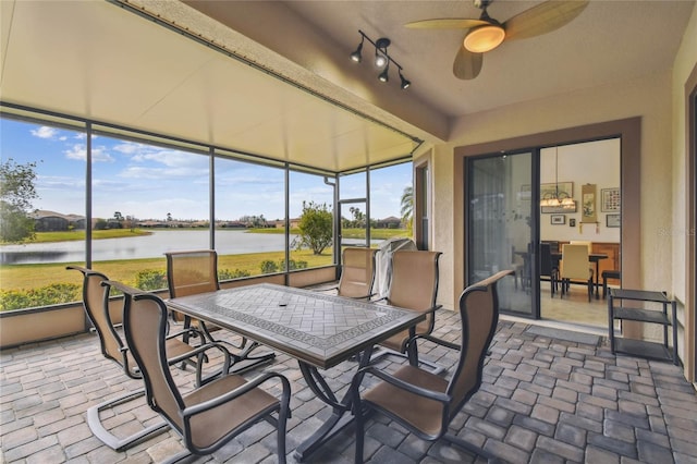 sunroom with ceiling fan, a healthy amount of sunlight, and a water view