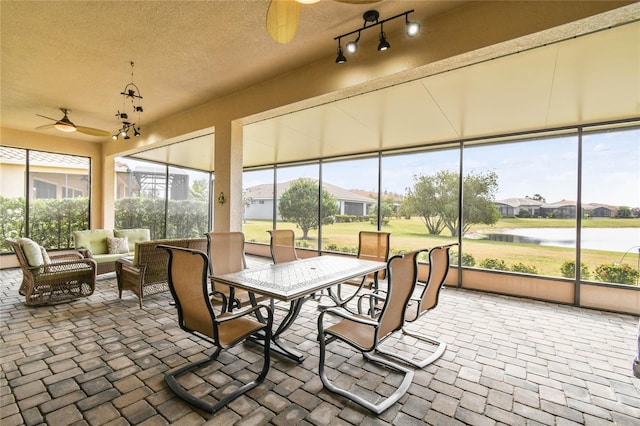 sunroom / solarium with ceiling fan and a water view