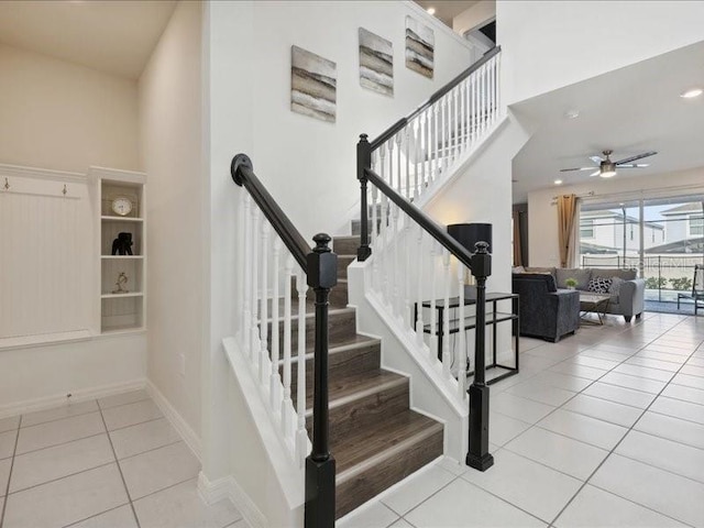 staircase featuring a towering ceiling, tile patterned floors, and ceiling fan