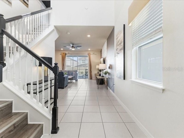 staircase with a high ceiling, tile patterned floors, and ceiling fan