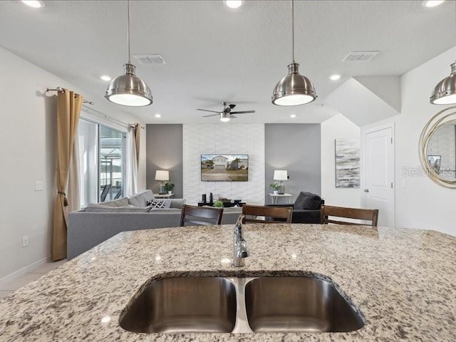 kitchen with pendant lighting, sink, and light stone counters