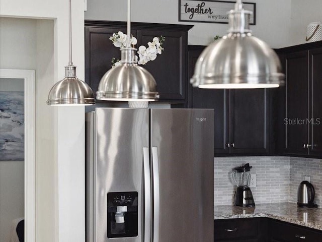 kitchen with light stone countertops, decorative backsplash, and stainless steel fridge with ice dispenser