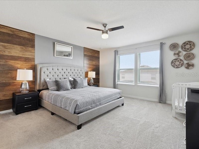 bedroom featuring wooden walls, light colored carpet, and ceiling fan