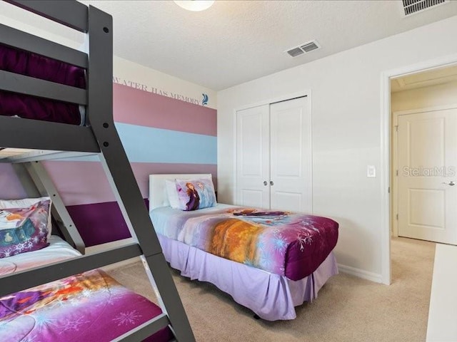 bedroom featuring light colored carpet, a textured ceiling, and a closet