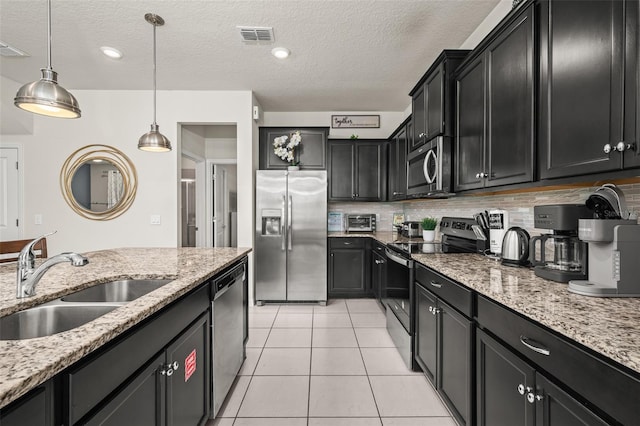 1607 Kona Ln, Davenport, FL 33897 - kitchen featuring stainless steel appliances, dark cabinets, hanging light fixtures, a textured ceiling, and light tile patterned flooring