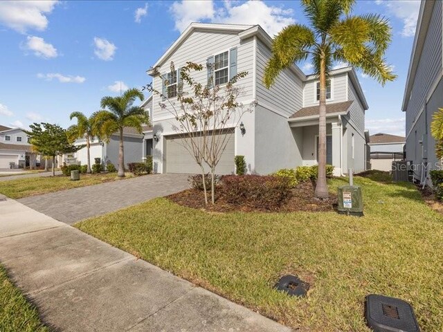 1607 Kona Ln, Davenport, FL 33897 - view of front of property featuring a garage, driveway, stucco siding, and a front lawn