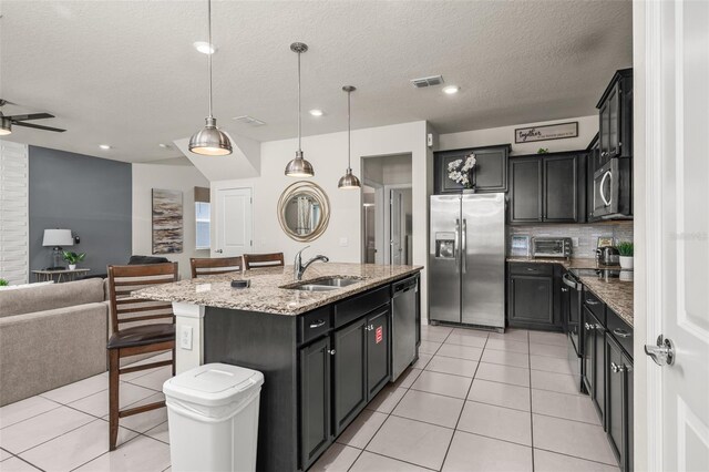 1607 Kona Ln, Davenport, FL 33897 - kitchen featuring appliances with stainless steel finishes, open floor plan, light stone counters, light tile patterned floors, and an island with sink