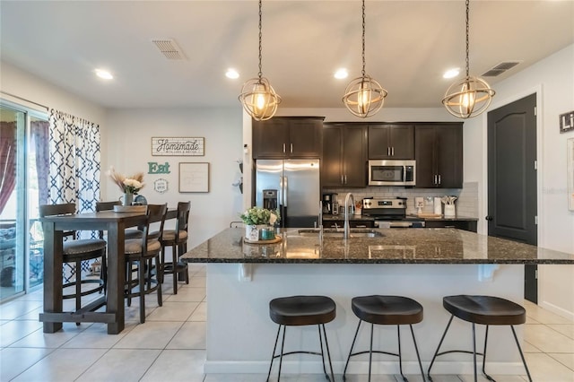 kitchen featuring appliances with stainless steel finishes, a center island with sink, dark brown cabinets, and sink