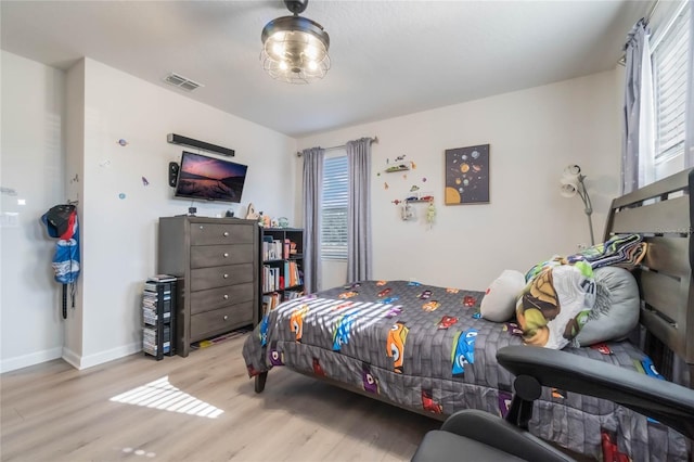 bedroom with light hardwood / wood-style floors and multiple windows