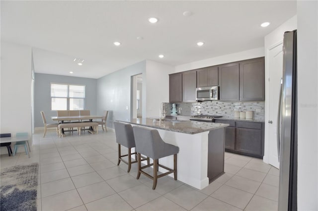 kitchen featuring sink, stone counters, appliances with stainless steel finishes, and light tile patterned floors