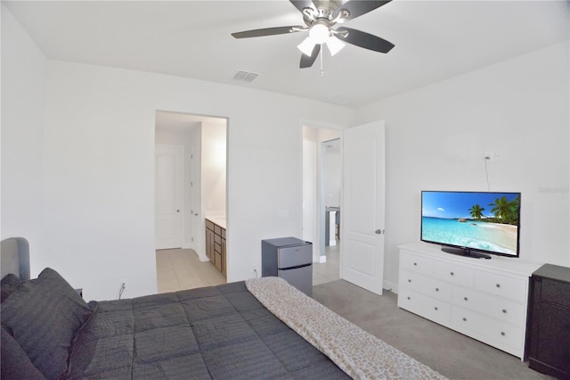 carpeted bedroom with ceiling fan, stainless steel refrigerator, and ensuite bathroom